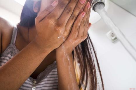 A teen rinsing her face in the sink