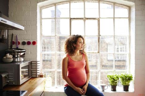 A pregnant woman sitting on a windowsill