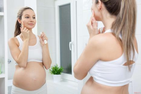 A pregnant woman putting cream on her face
