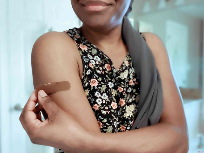 Woman Applies Bandage to Upper Arm - stock photo