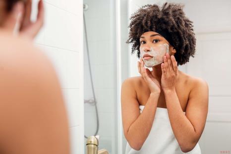 Teenager Applying Facial Mask While Looking In Mirror At Bathroom