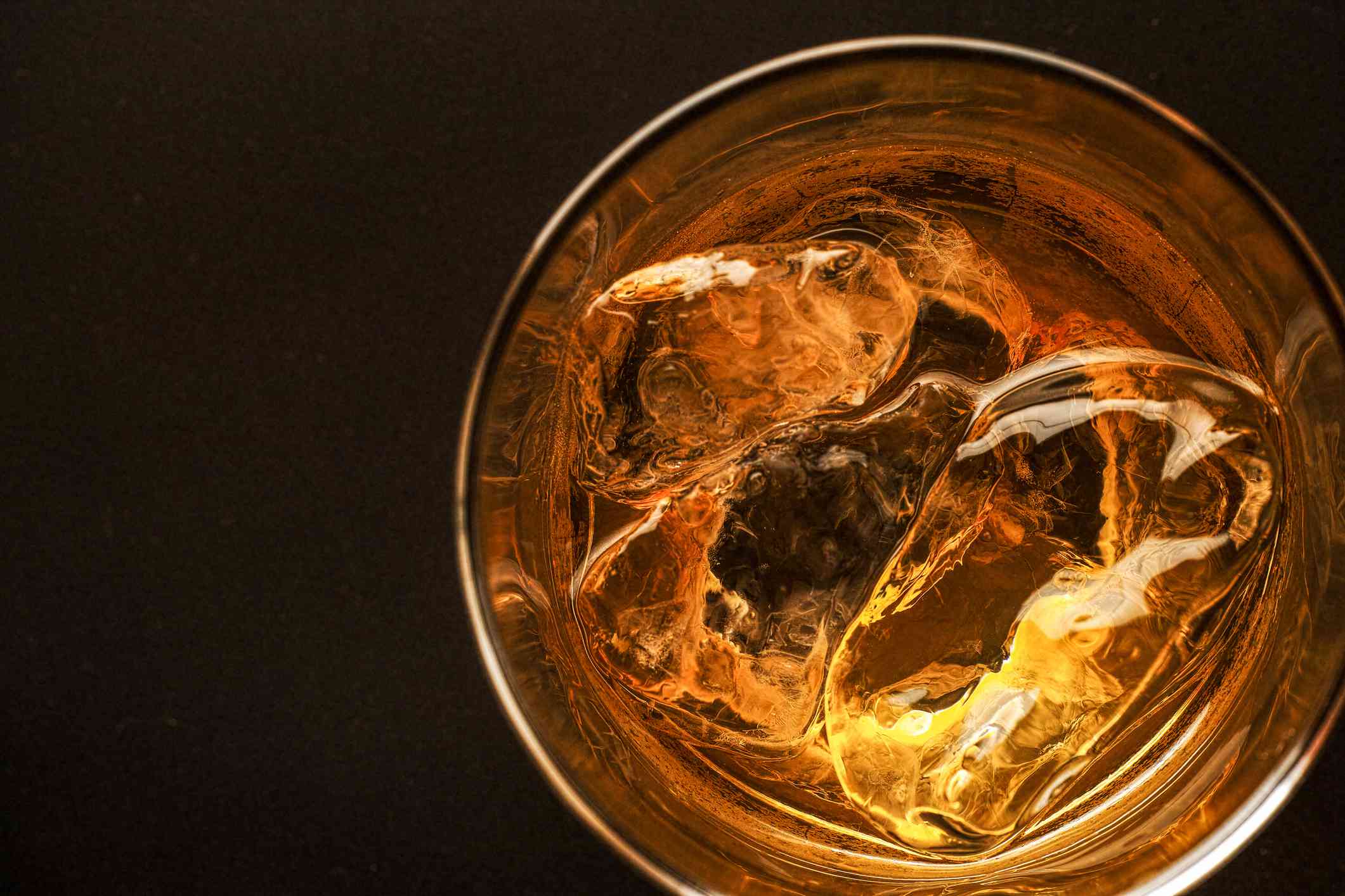 Full whiskey glass on a black background as seen from above