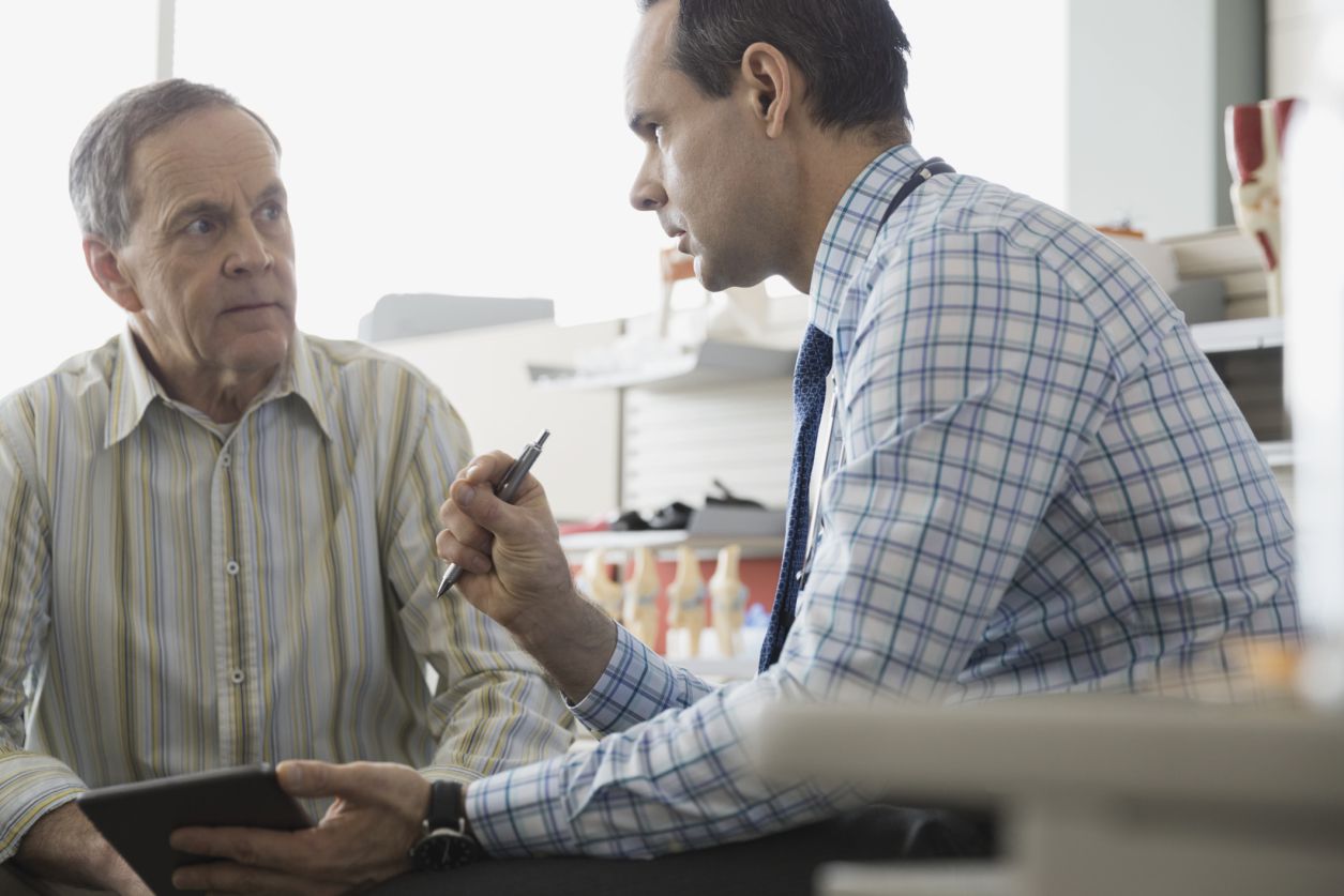 Doctor talking with older male patient in office