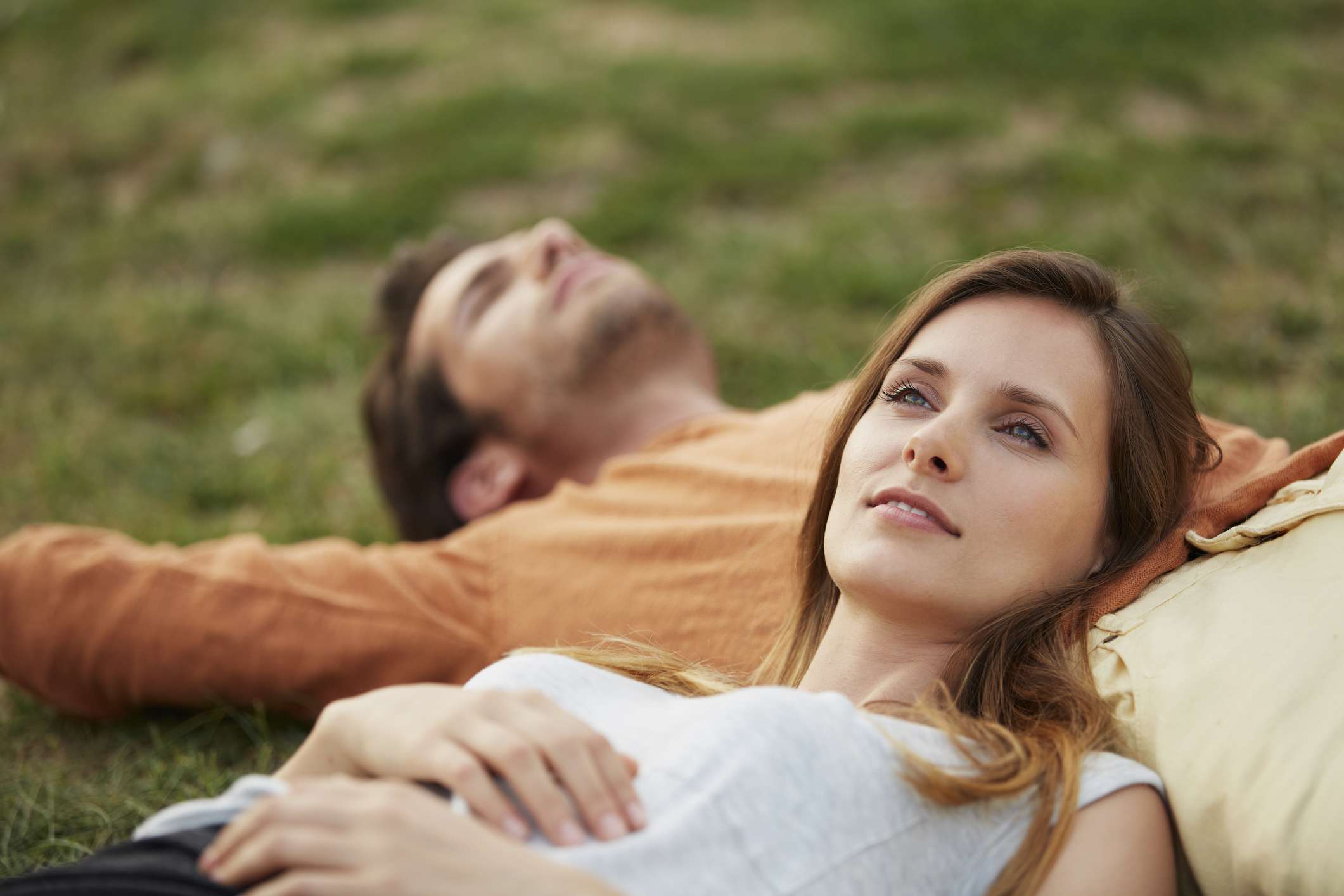 Woman resting head on man's stomach at park