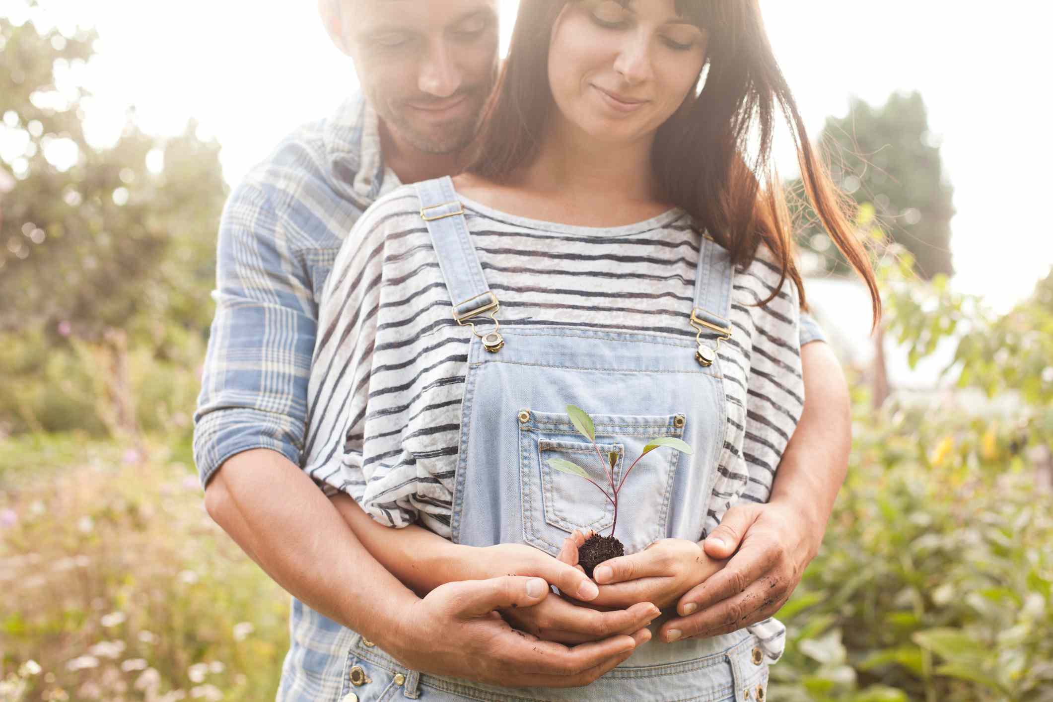 Couple hugging and looking at seedling