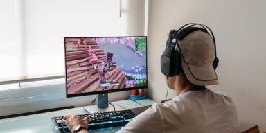 Teenager playing Fortnite video game on PC. Fortnite is an o<em></em>nline multiplayer video game developed by Epic Games