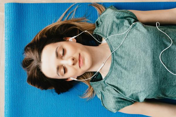 Woman asleep on yoga mat wearing earphones