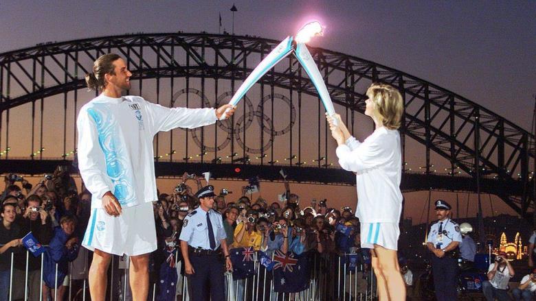 Pat Rafter and Olivia Newton-John hold the Olympic torch in front of the Sydney Harbour Bridge